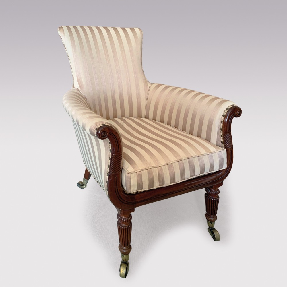 A 19th-century Regency mahogany tub chair featuring beige striped upholstery, scrolled lyre front arm supports, reeded legs, and brass castors.