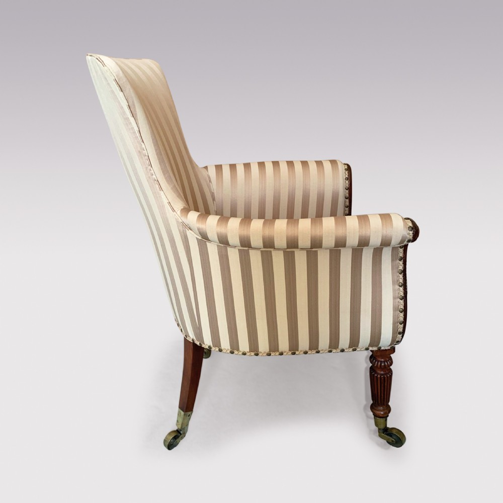 A 19th-century Regency mahogany tub chair featuring beige striped upholstery, scrolled lyre front arm supports, reeded legs, and brass castors. View IV