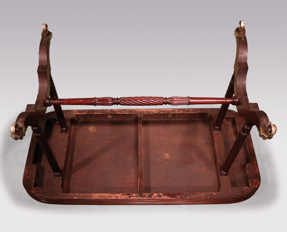 A dark mahogany Regency writing table featuring a rectangular top with rounded corners, spiral-turned end supports, a low stretcher, and brass paw castors. View IV