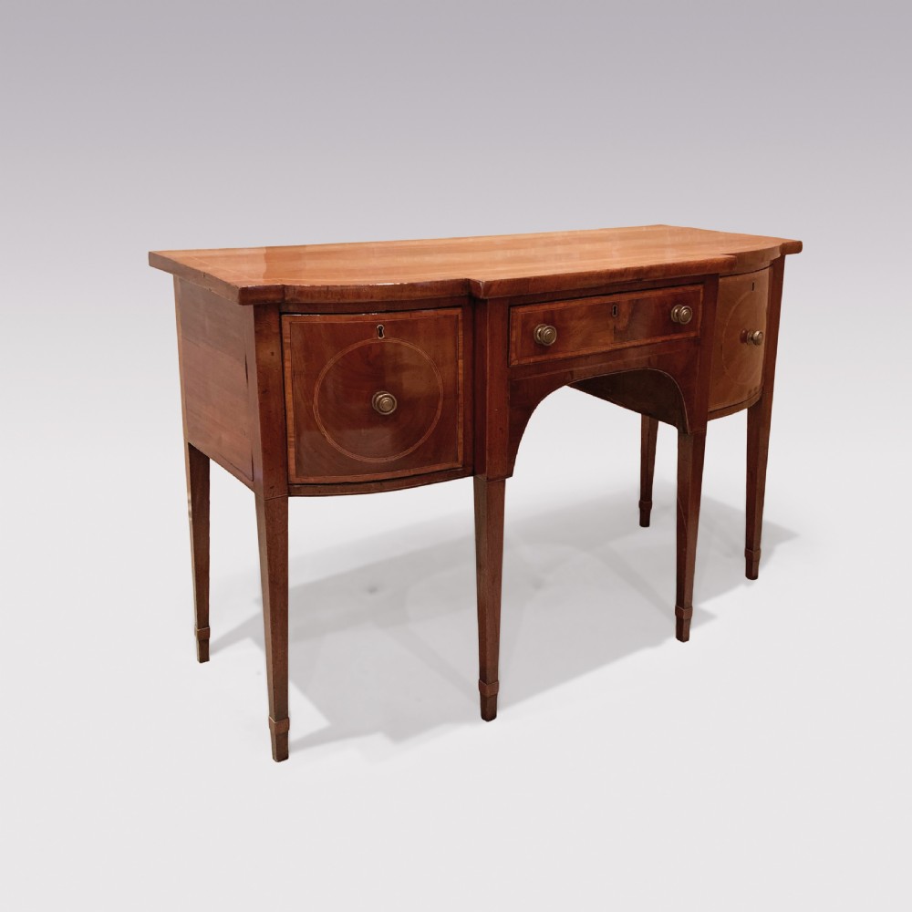 An eighteenth-century Sheraton mahogany sideboard featuring a central drawer flanked by circular inlaid cupboards, supported on slender tapered legs. View II