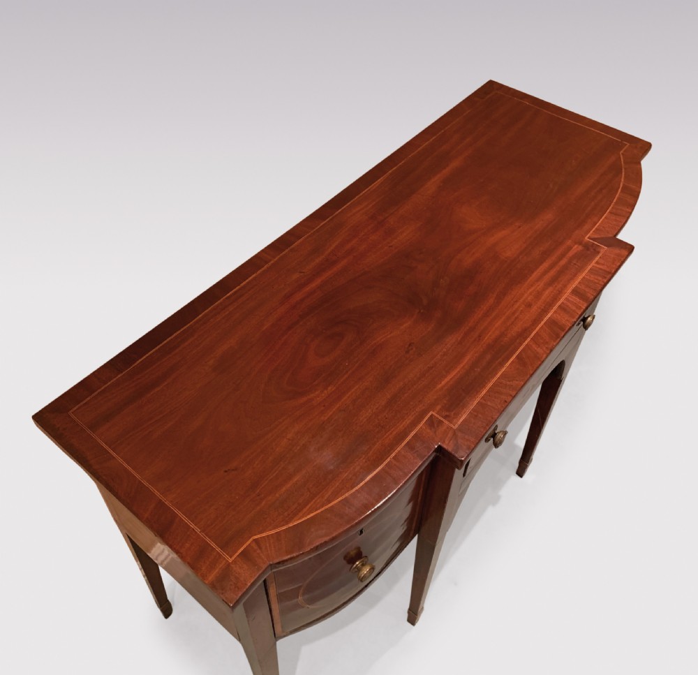 An eighteenth-century Sheraton mahogany sideboard featuring a central drawer flanked by circular inlaid cupboards, supported on slender tapered legs. View III