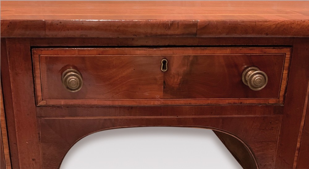An eighteenth-century Sheraton mahogany sideboard featuring a central drawer flanked by circular inlaid cupboards, supported on slender tapered legs. View VI