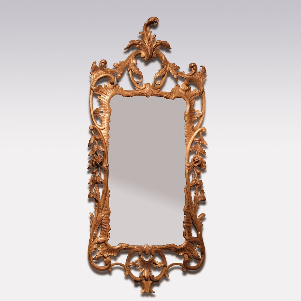 A mid-18th-century Chippendale period gilded wall mirror featuring intricate pierced Rococo scrollwork, carved acanthus leaves, and a central reflective glass panel.