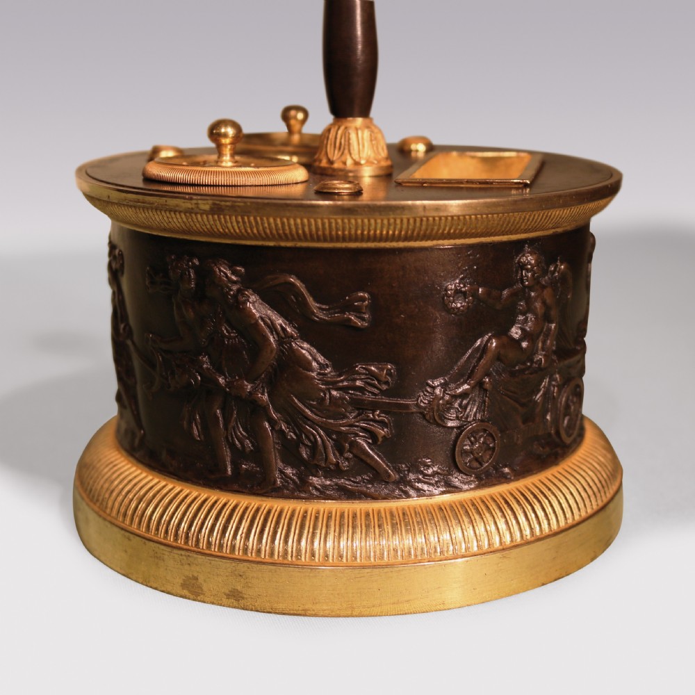 A 19th-century cylindrical French patinated bronze encrier featuring a classical relief frieze, gilded bronze borders, inkwell lids, and a central column handle. View II