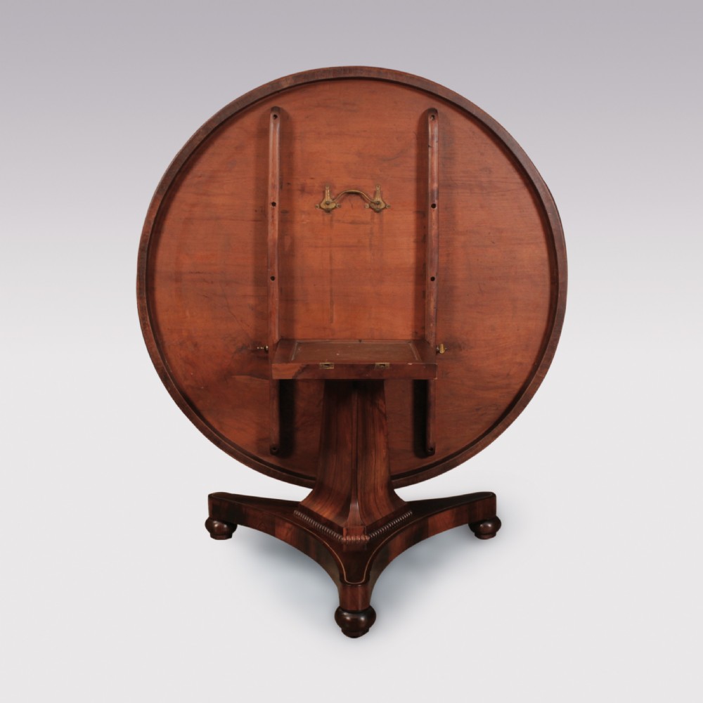 A circular Regency rosewood centre table featuring decorative brass inlay around the perimeter and supported by a pedestal on a triform base. View III