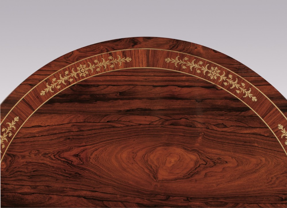 A circular Regency rosewood centre table featuring decorative brass inlay around the perimeter and supported by a pedestal on a triform base. View V