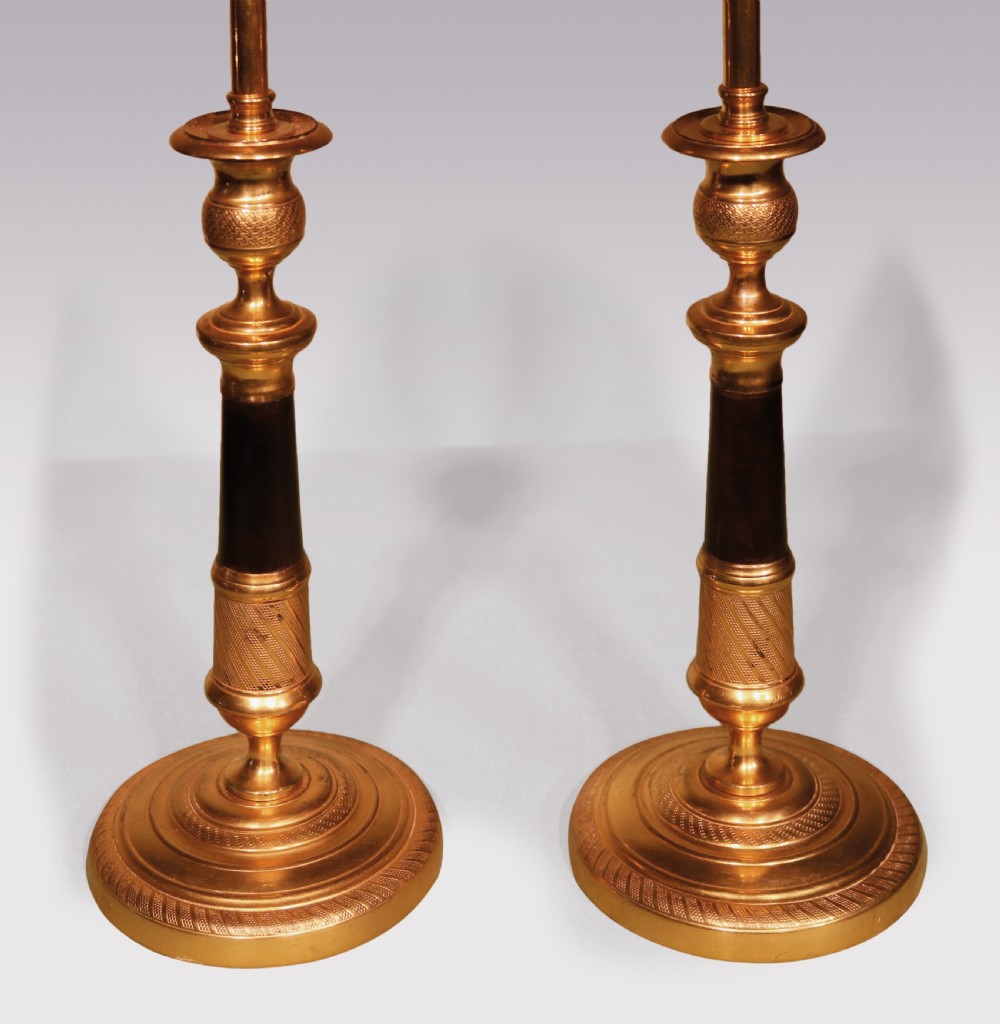 A pair of early 19th-century bronze and ormolu candlestick lamps with dark shafts, gilded bases, and pink pleated fabric lampshades. View II