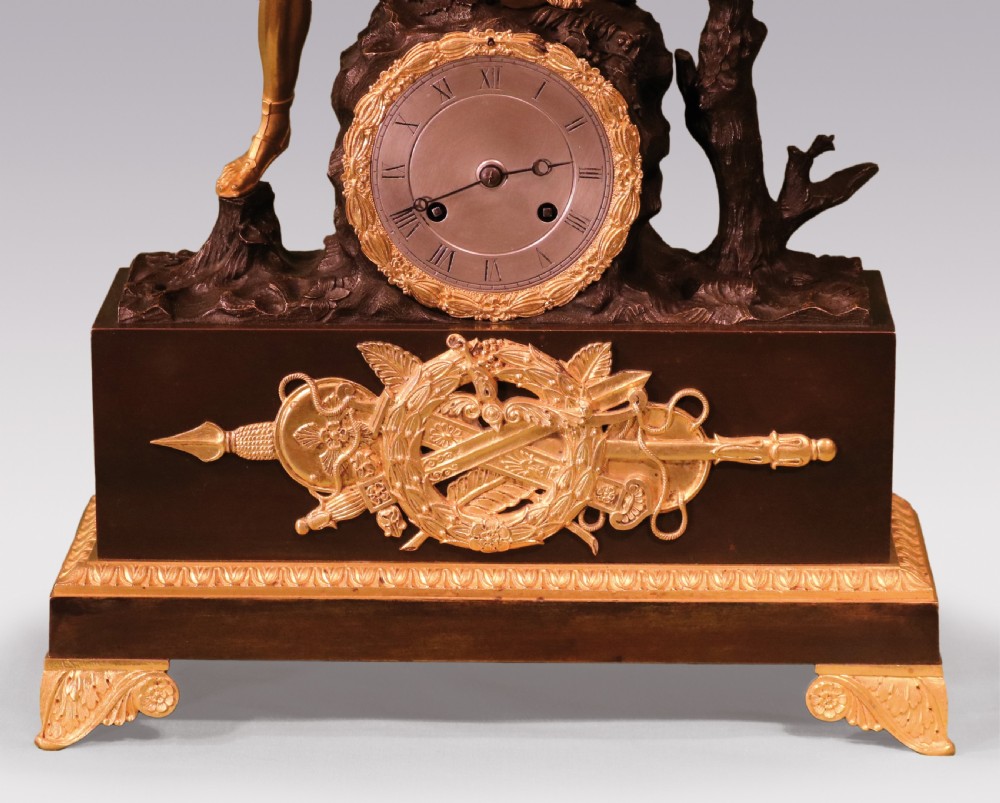 An early 19th-century French Empire clock crafted from gilt and patinated bronze, featuring a classical warrior figure standing beside a tree with a serpent atop a rectangular plinth. View III