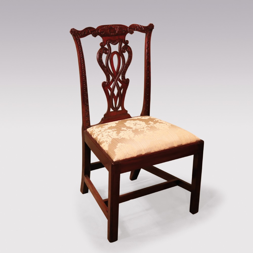 A pair of Georgian Chippendale carved mahogany single dining chairs featuring detailed pierced splats and patterned fabric upholstered seats. View V