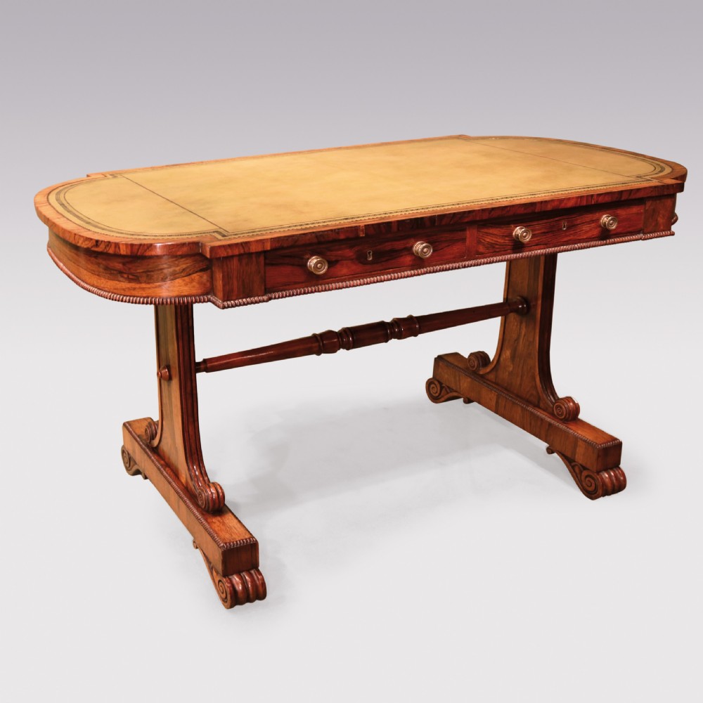 An early 19th-century Regency rosewood writing table featuring a green leather-inset top, two frieze drawers with brass handles, and trestle-end supports connected by a turned stretcher. View II