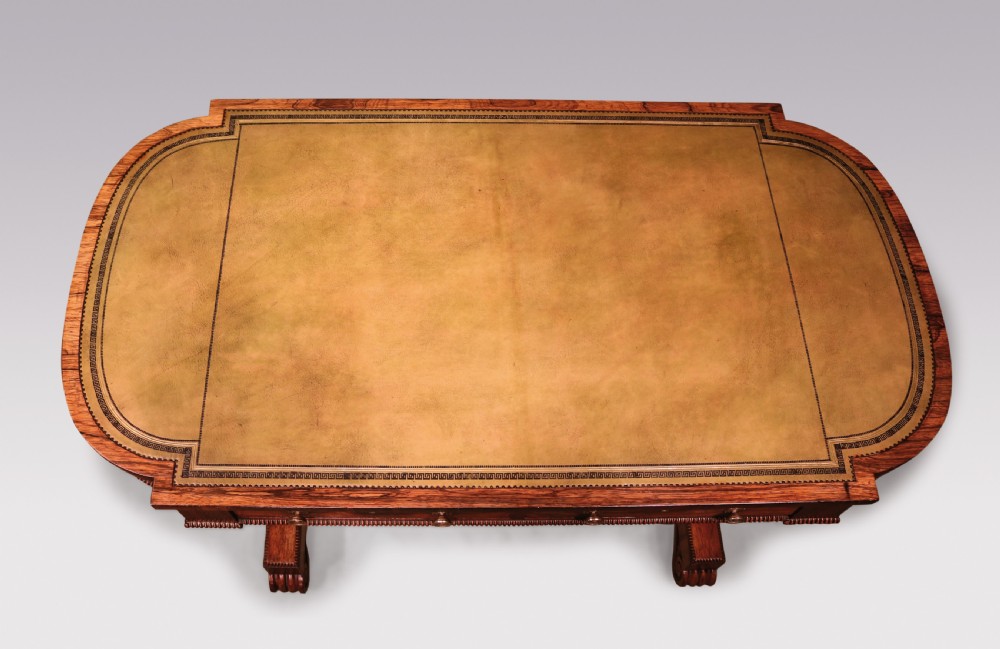 An early 19th-century Regency rosewood writing table featuring a green leather-inset top, two frieze drawers with brass handles, and trestle-end supports connected by a turned stretcher. View III