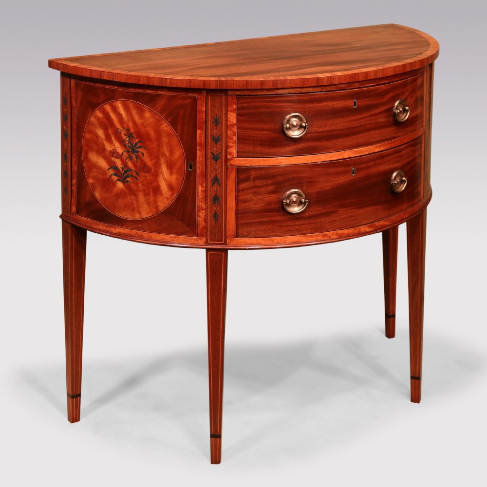 A late 18th-century Sheraton period demilune commode crafted from satinwood with floral marquetry panels and tapered legs.