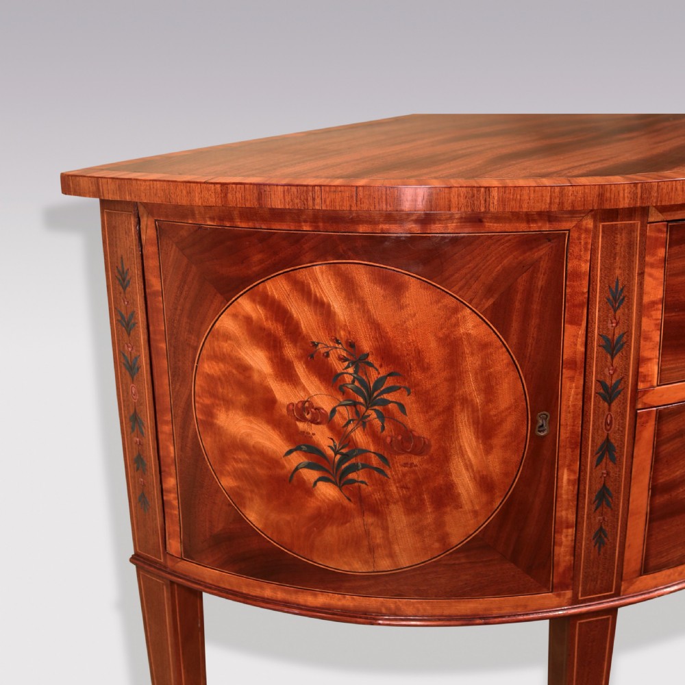 A late 18th-century Sheraton period demilune commode crafted from satinwood with floral marquetry panels and tapered legs. View IV
