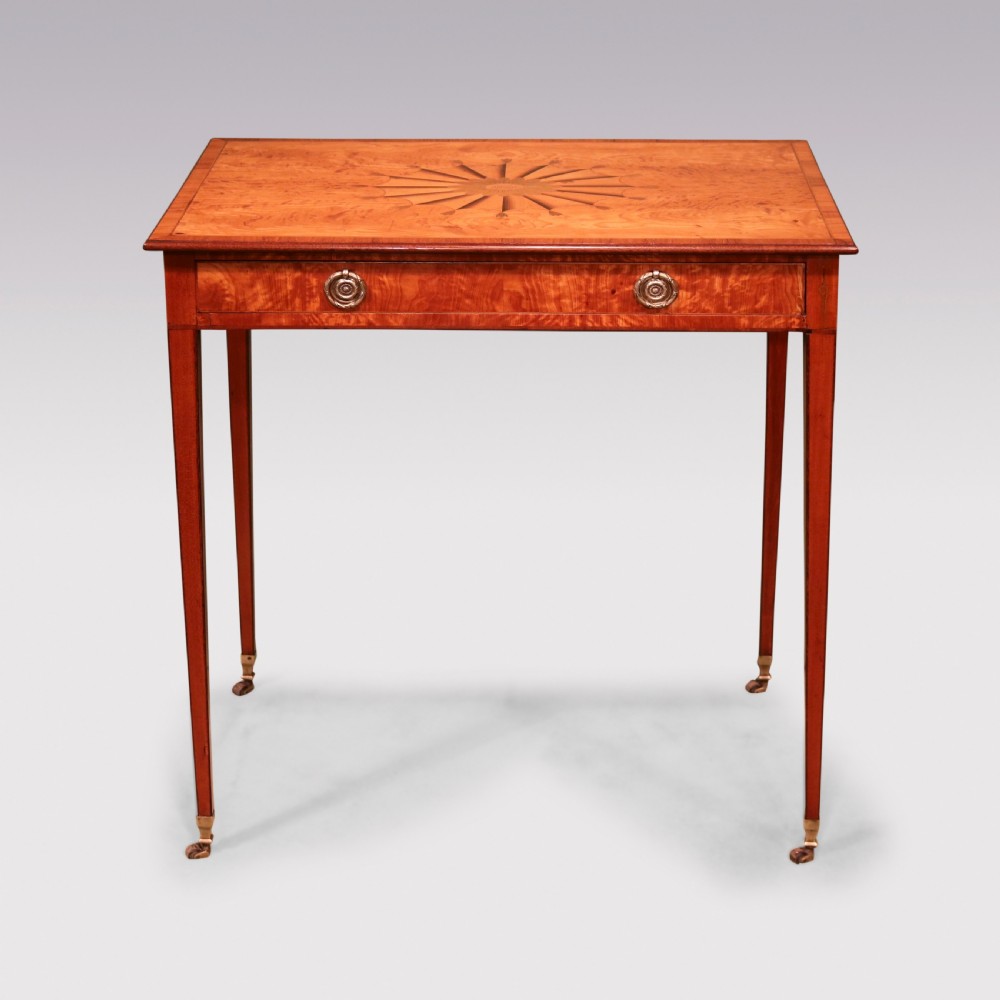 A late 18th-century Sheraton period satinwood side table featuring a starburst marquetry top, single drawer with ring pull handles, and square tapered legs on brass castors. View II