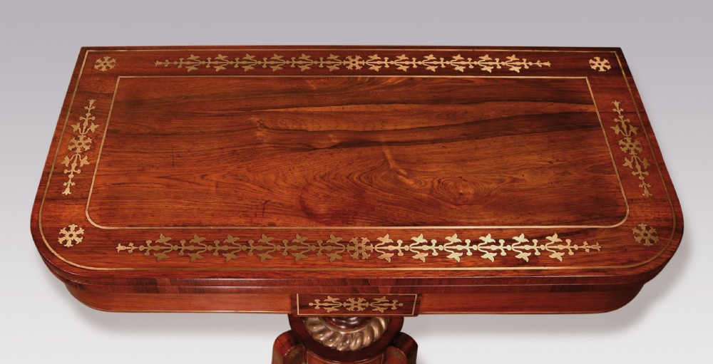 A pair of Regency period rosewood card tables featuring brass inlaid tops, turned central pedestals, and four splayed legs with brass paw feet. View IV