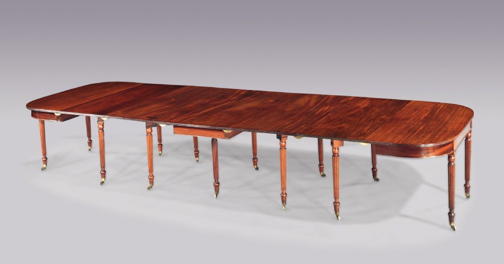 A long Regency period mahogany extending dining table with reeded legs ending in brass castors.