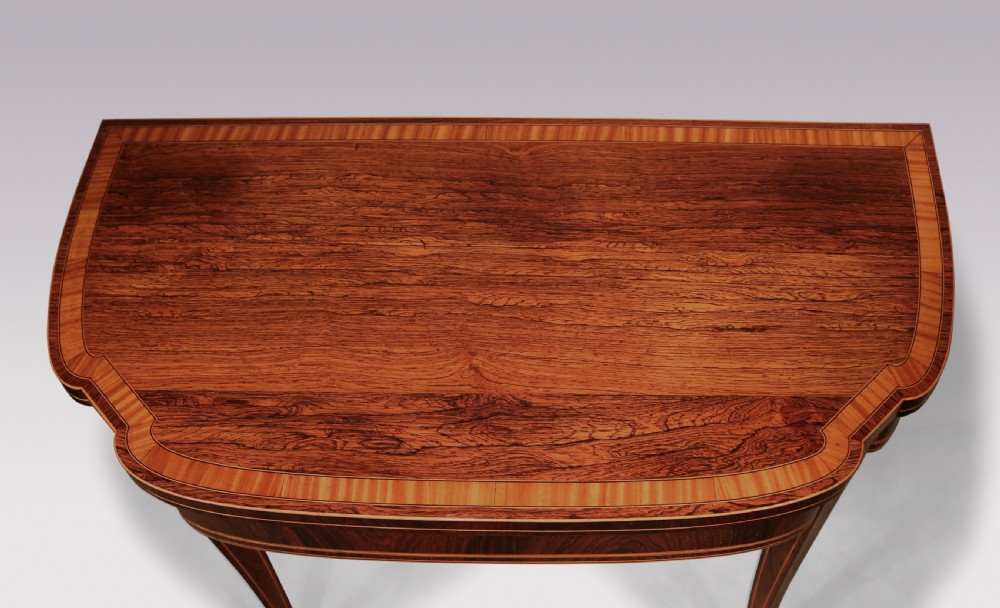 An antique Sheraton period rosewood fold-over card table featuring intricate marquetry stringing, diamond inlay accents, and tapered legs. View IV