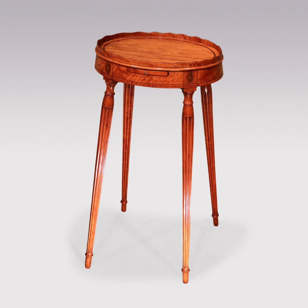 A George III oval satinwood kettle stand featuring a scalloped gallery rim, fluted tapered legs, and an inlaid apron with a pull-out slide. View II