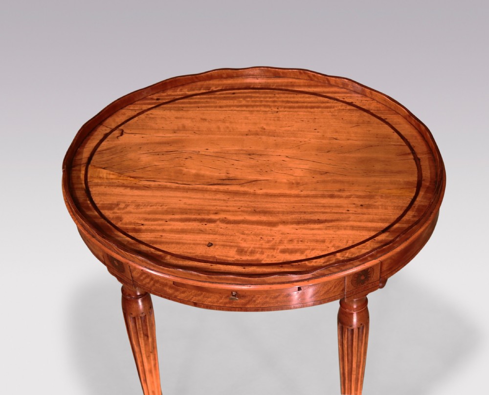 A George III oval satinwood kettle stand featuring a scalloped gallery rim, fluted tapered legs, and an inlaid apron with a pull-out slide. View V