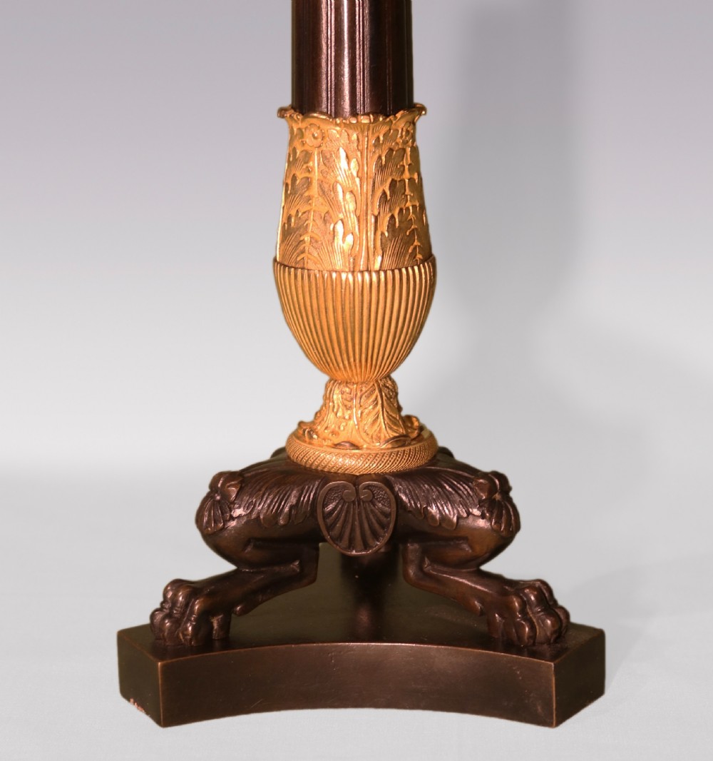 A pair of patinated bronze and gilt ormolu candlestick table lamps with fluted shafts, lion paw bases, and flared pleated fabric shades. View IV