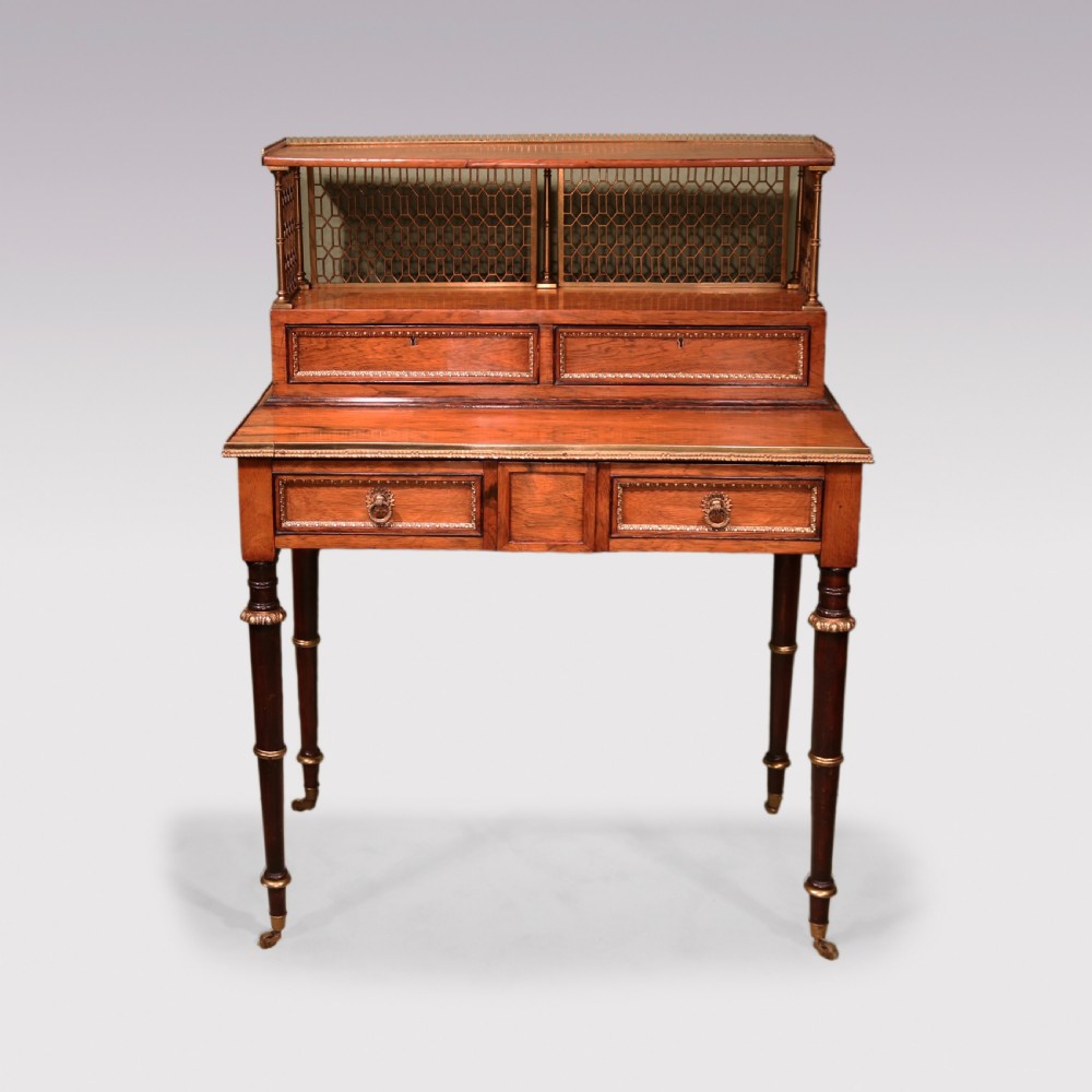 An early nineteenth-century rosewood bonheur du jour writing desk featuring a pierced brass gallery top, small drawers, brass mounts, and turned legs with castors. View II