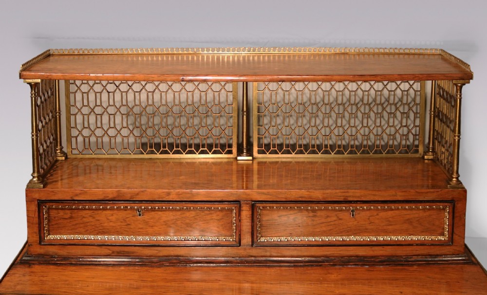 An early nineteenth-century rosewood bonheur du jour writing desk featuring a pierced brass gallery top, small drawers, brass mounts, and turned legs with castors. View III