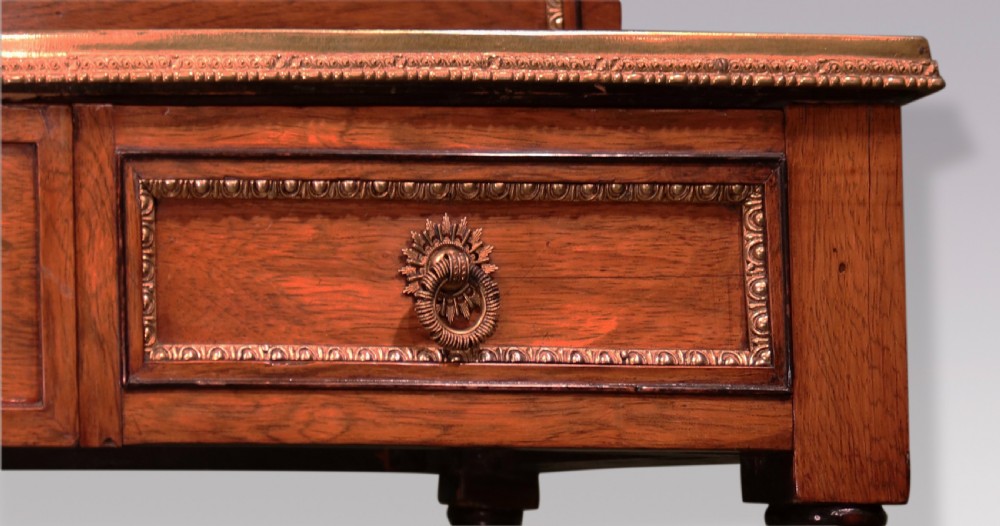An early nineteenth-century rosewood bonheur du jour writing desk featuring a pierced brass gallery top, small drawers, brass mounts, and turned legs with castors. View VI
