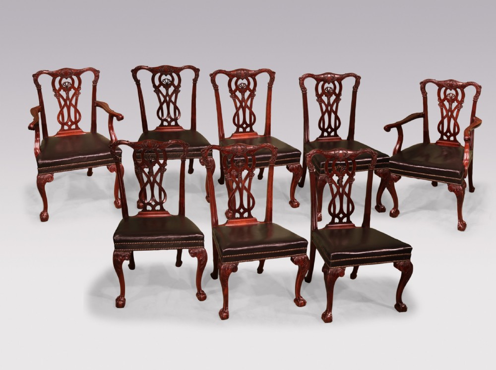 A set of eight mahogany dining chairs comprising six side chairs and two carvers with intricate pierced back splats, dark leather seats, and carved cabriole legs ending in ball and claw feet.