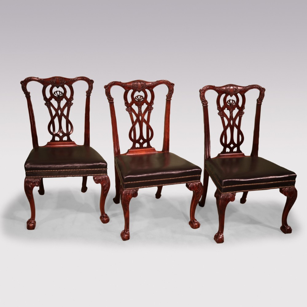 A set of eight mahogany dining chairs comprising six side chairs and two carvers with intricate pierced back splats, dark leather seats, and carved cabriole legs ending in ball and claw feet. View II