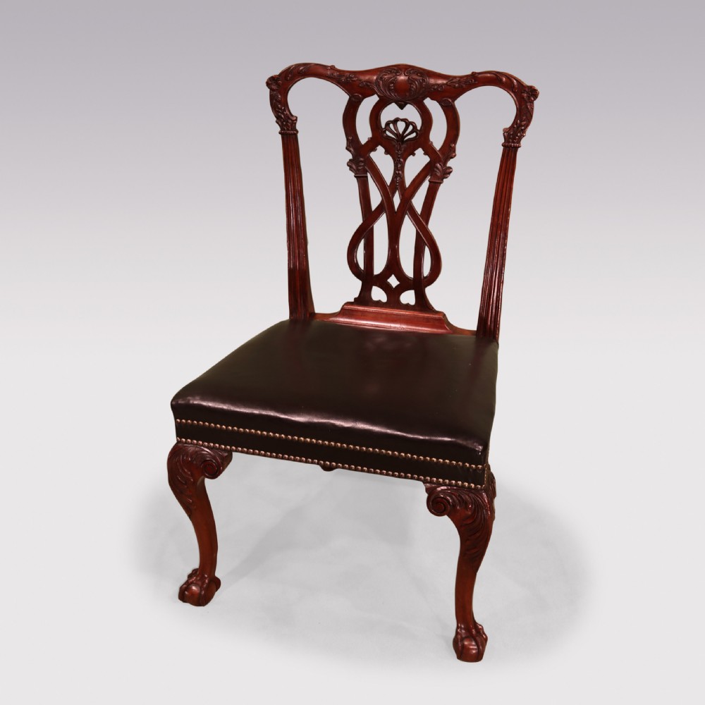 A set of eight mahogany dining chairs comprising six side chairs and two carvers with intricate pierced back splats, dark leather seats, and carved cabriole legs ending in ball and claw feet. View V