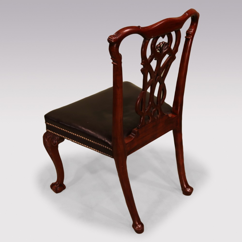 A set of eight mahogany dining chairs comprising six side chairs and two carvers with intricate pierced back splats, dark leather seats, and carved cabriole legs ending in ball and claw feet. View VI