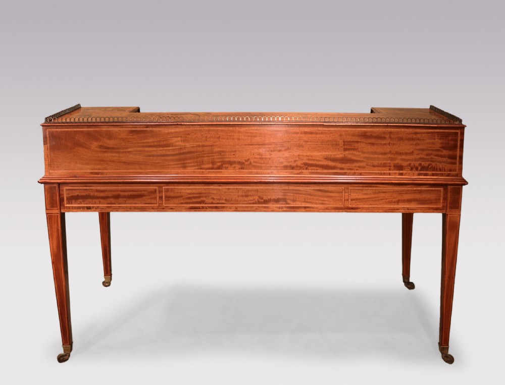 A George III mahogany Carlton House writing desk featuring a U-shaped tiered gallery with drawers, a leather writing top, and tapered legs on castors. View III