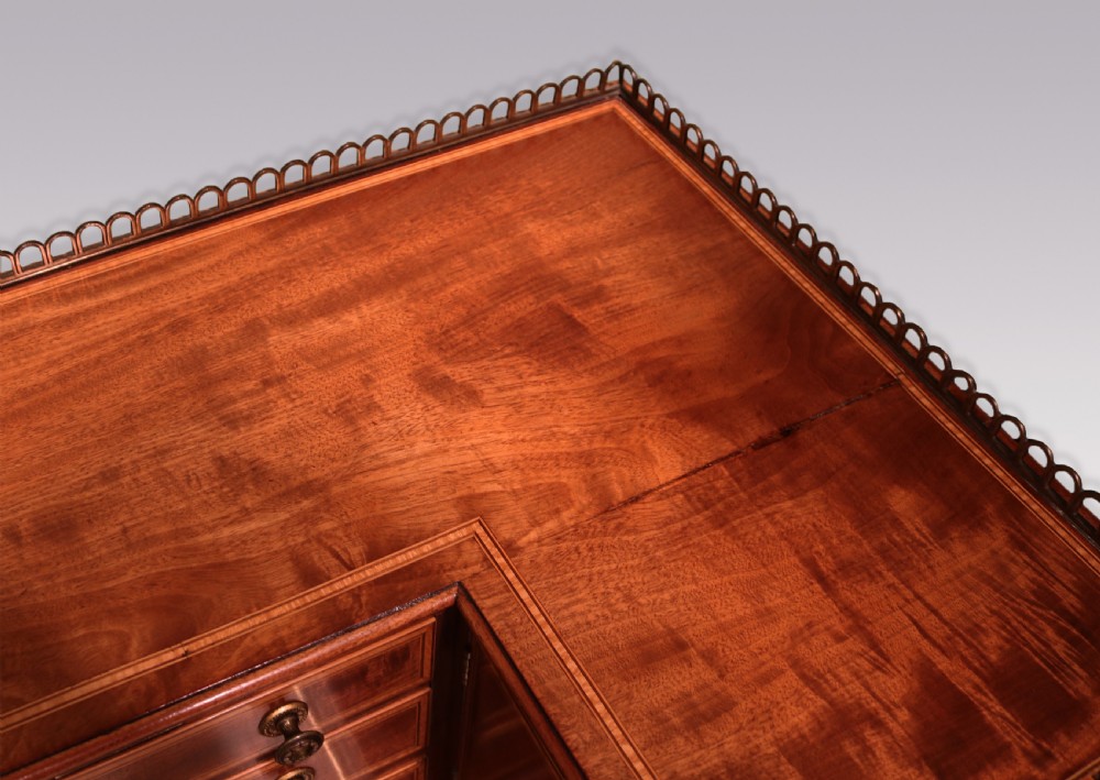 A George III mahogany Carlton House writing desk featuring a U-shaped tiered gallery with drawers, a leather writing top, and tapered legs on castors. View VII