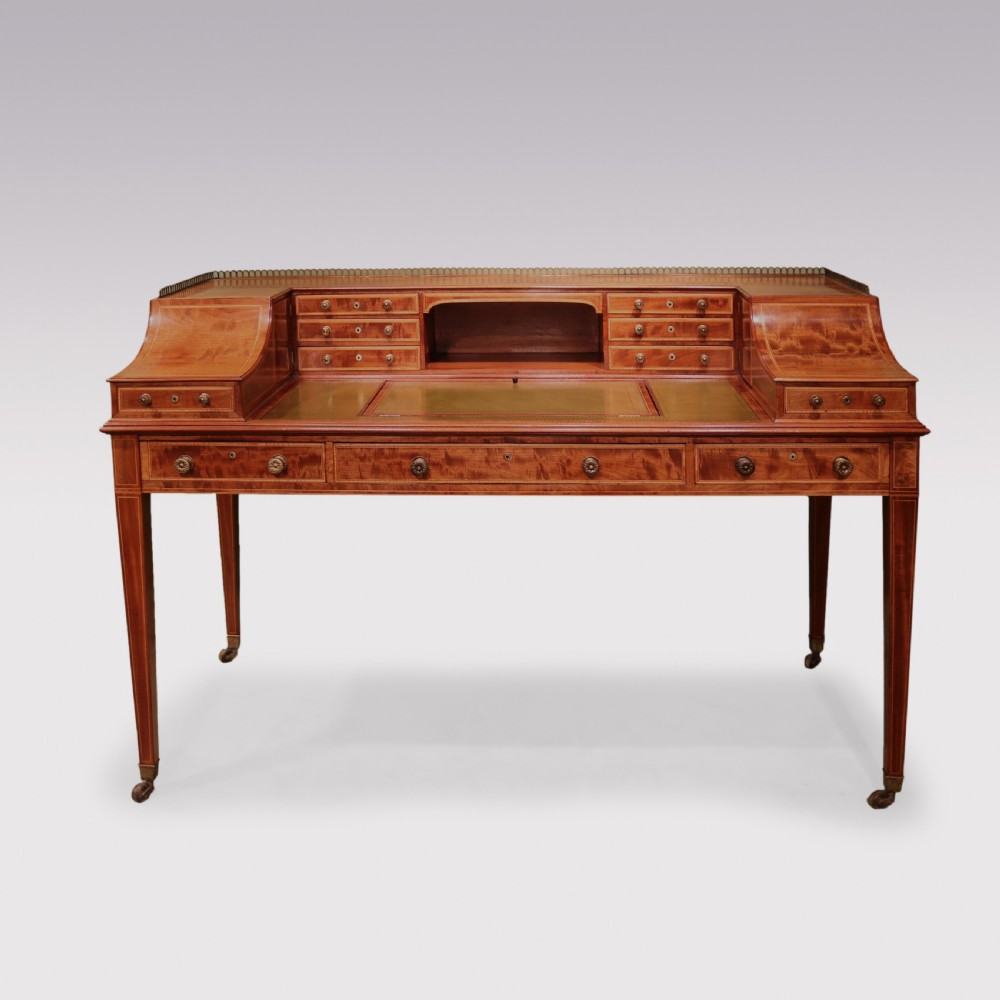 A George III mahogany Carlton House writing desk featuring a U-shaped tiered gallery with drawers, a leather writing top, and tapered legs on castors. View IX