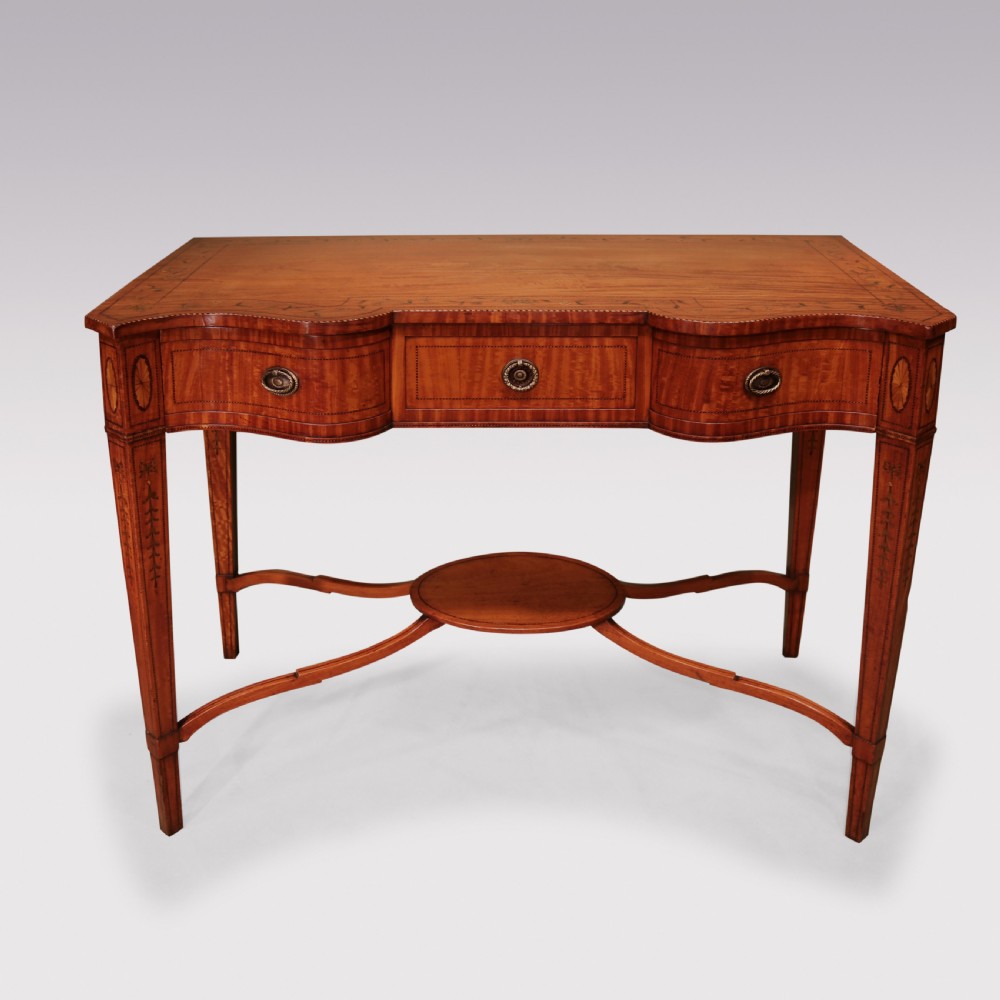 A late 19th-century satinwood hall table featuring a serpentine front, three drawers with brass handles, floral marquetry inlay on square tapered legs, and a central circular under-shelf connected by curved stretchers. View II