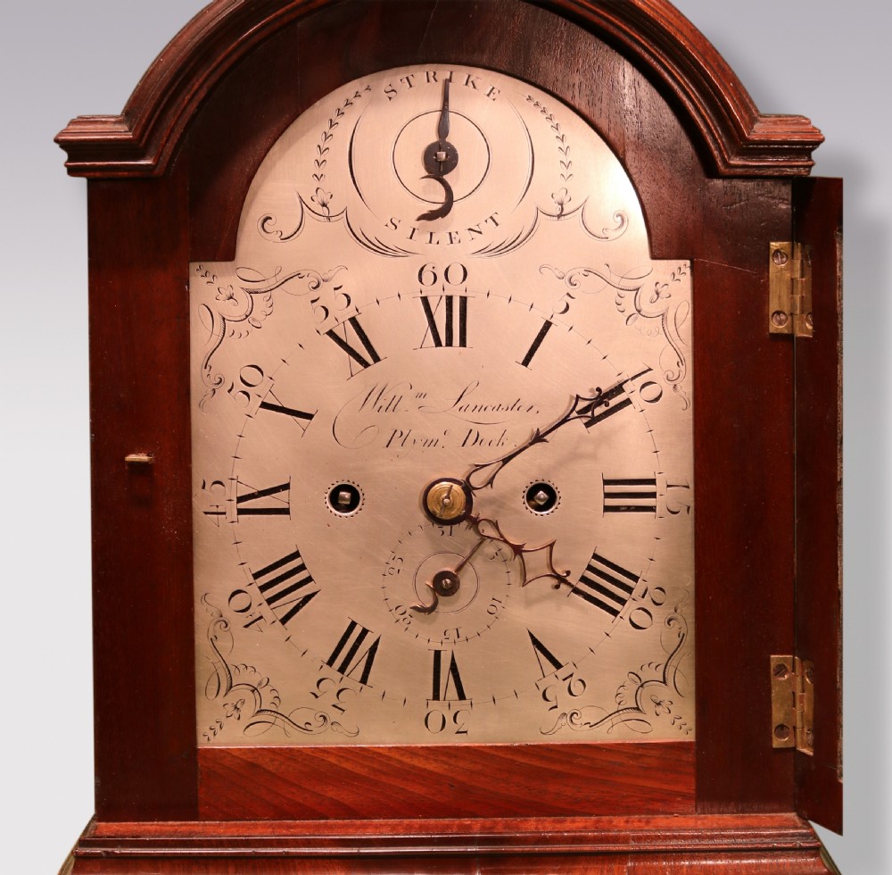 A George III mahogany bracket clock featuring an arched top with a brass carrying handle, an engraved silvered dial with Roman numerals, and brass bracket feet. View II