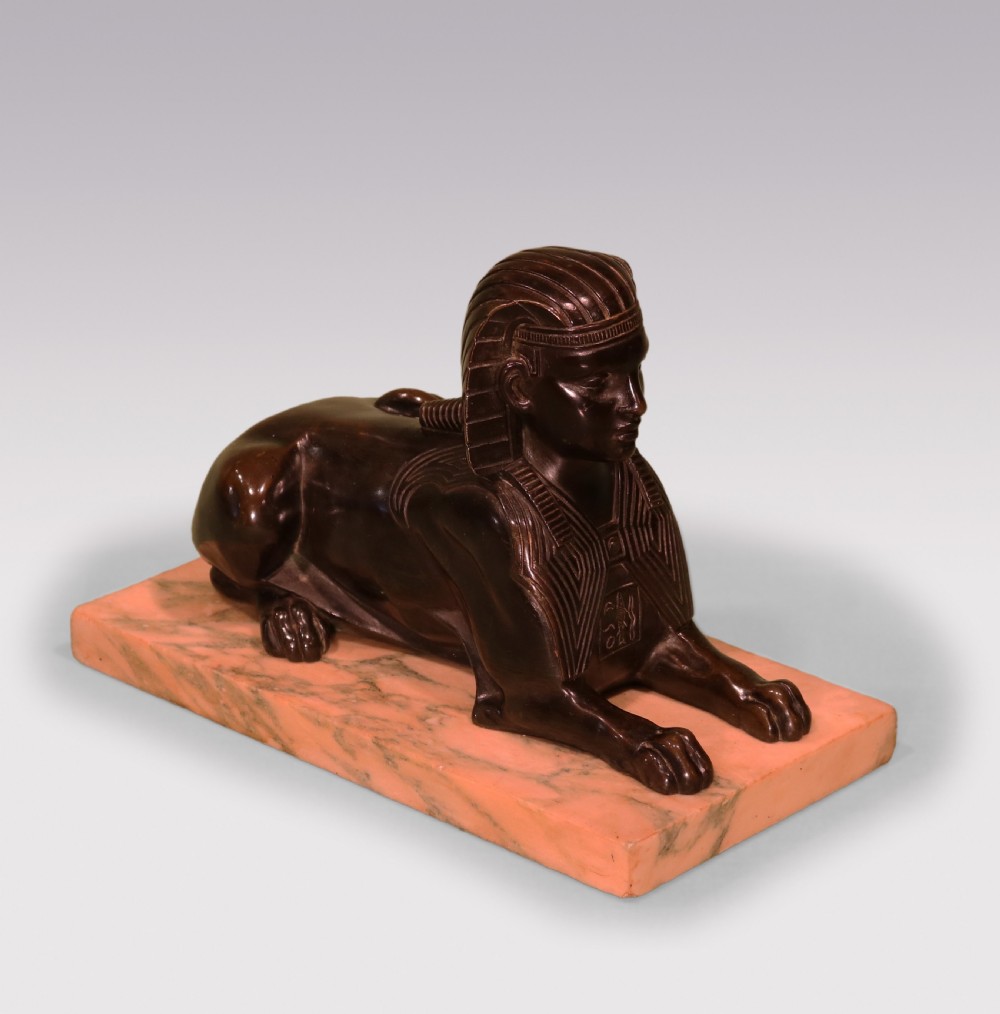 A Regency period dark bronze sphinx sculpture mounted on a rectangular veined cream marble base. View II