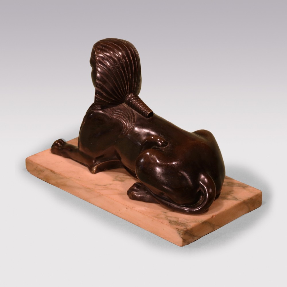 A Regency period dark bronze sphinx sculpture mounted on a rectangular veined cream marble base. View IV