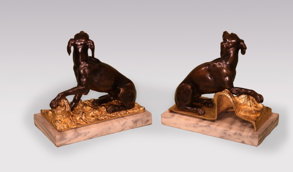 A pair of 19th-century dark bronze sculptures featuring seated hounds resting their paws on gilded ormolu bases depicting pheasants, mounted on rectangular marble plinths. View IV