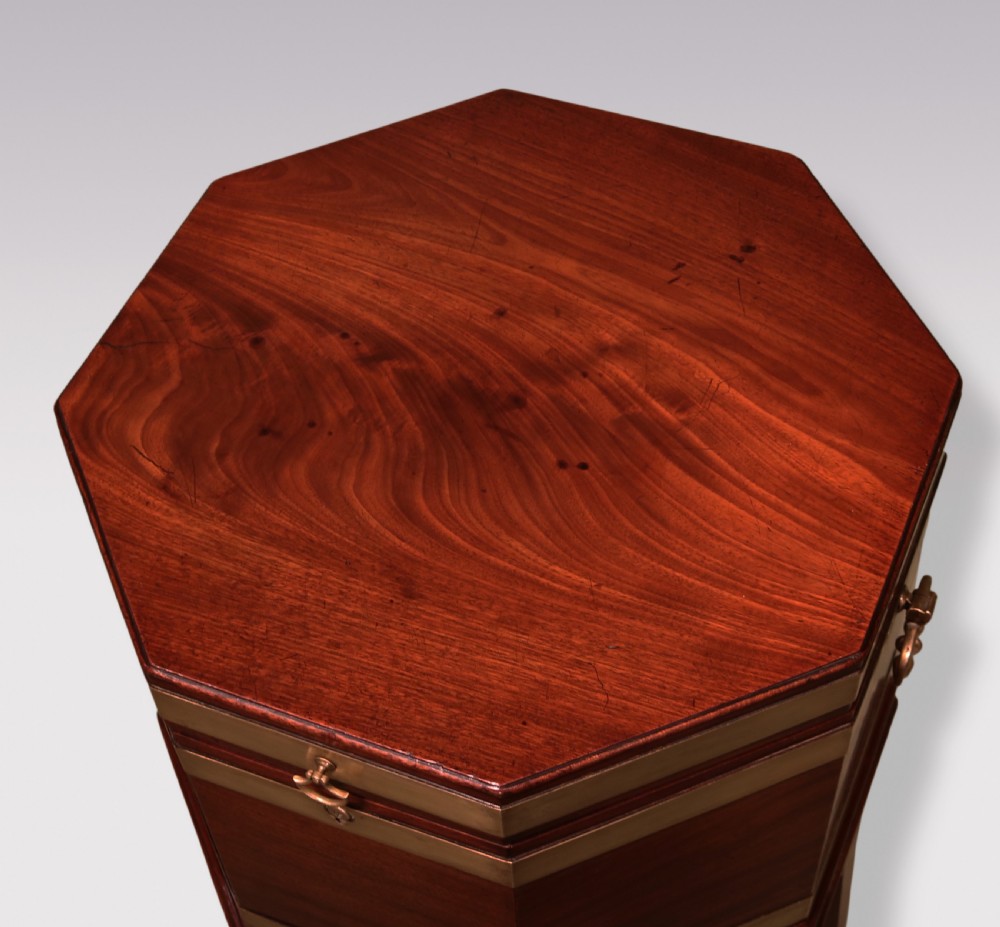 An octagonal George III mahogany wine cooler featuring brass straps, side drop handles, hinged lid, and tapered legs on castors. View II