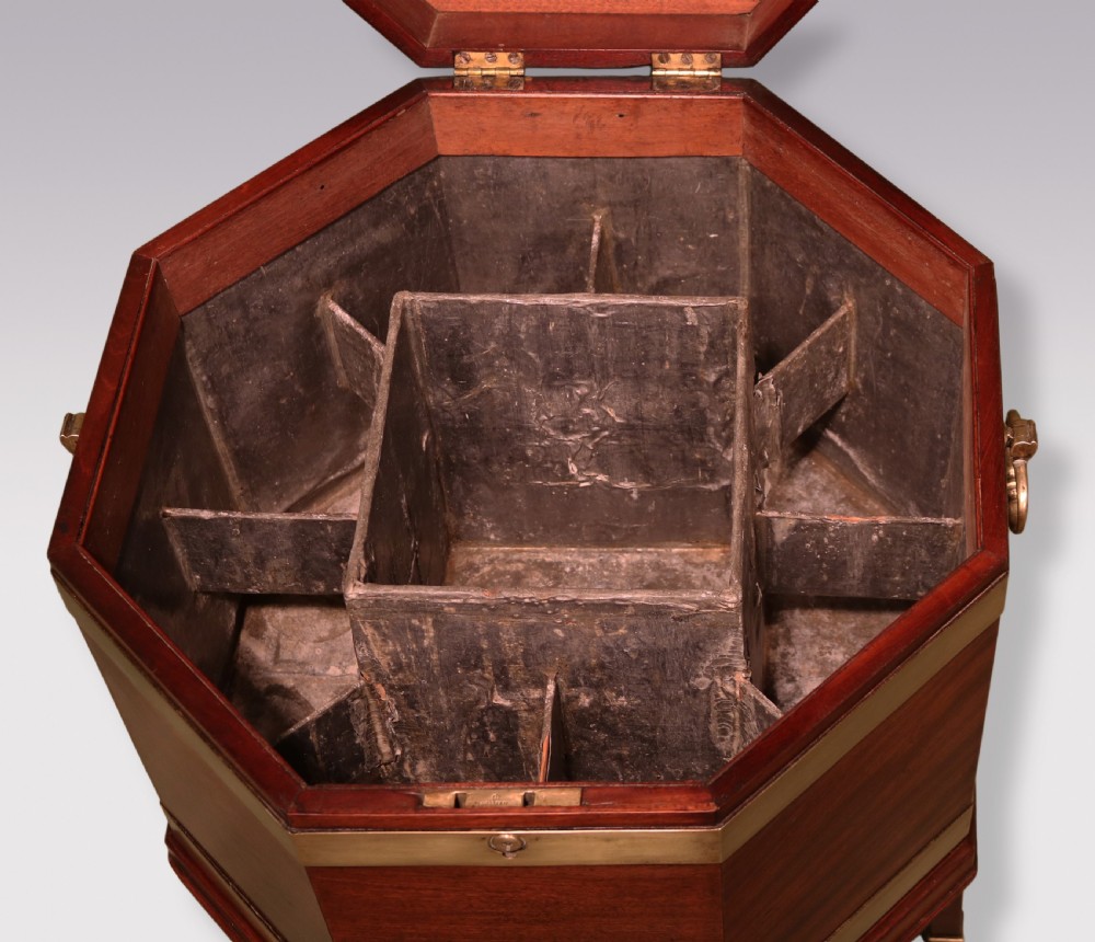An octagonal George III mahogany wine cooler featuring brass straps, side drop handles, hinged lid, and tapered legs on castors. View III