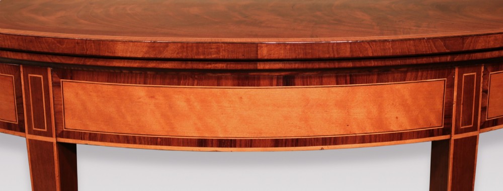 A demilune mahogany card table with satinwood crossbanding inlay and tapered square legs. View IV
