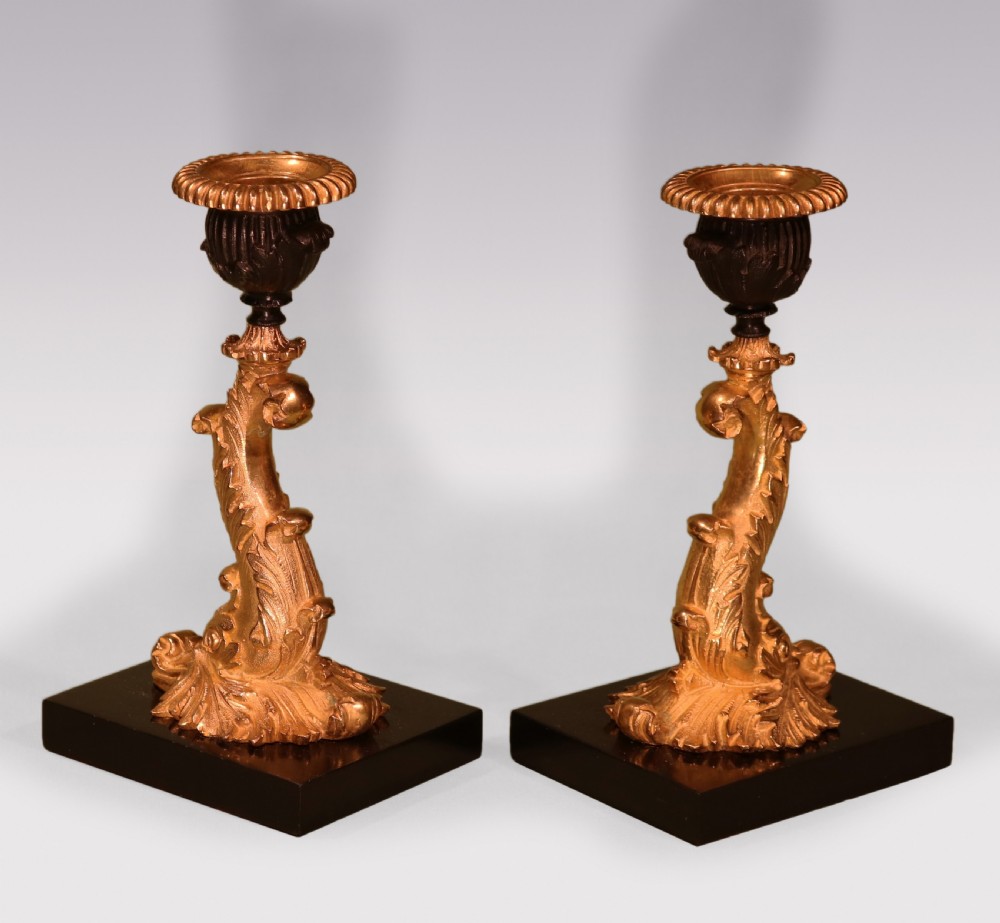 A pair of early nineteenth-century gilt bronze candlesticks featuring stylised dolphin stems resting on square black marble bases. View II