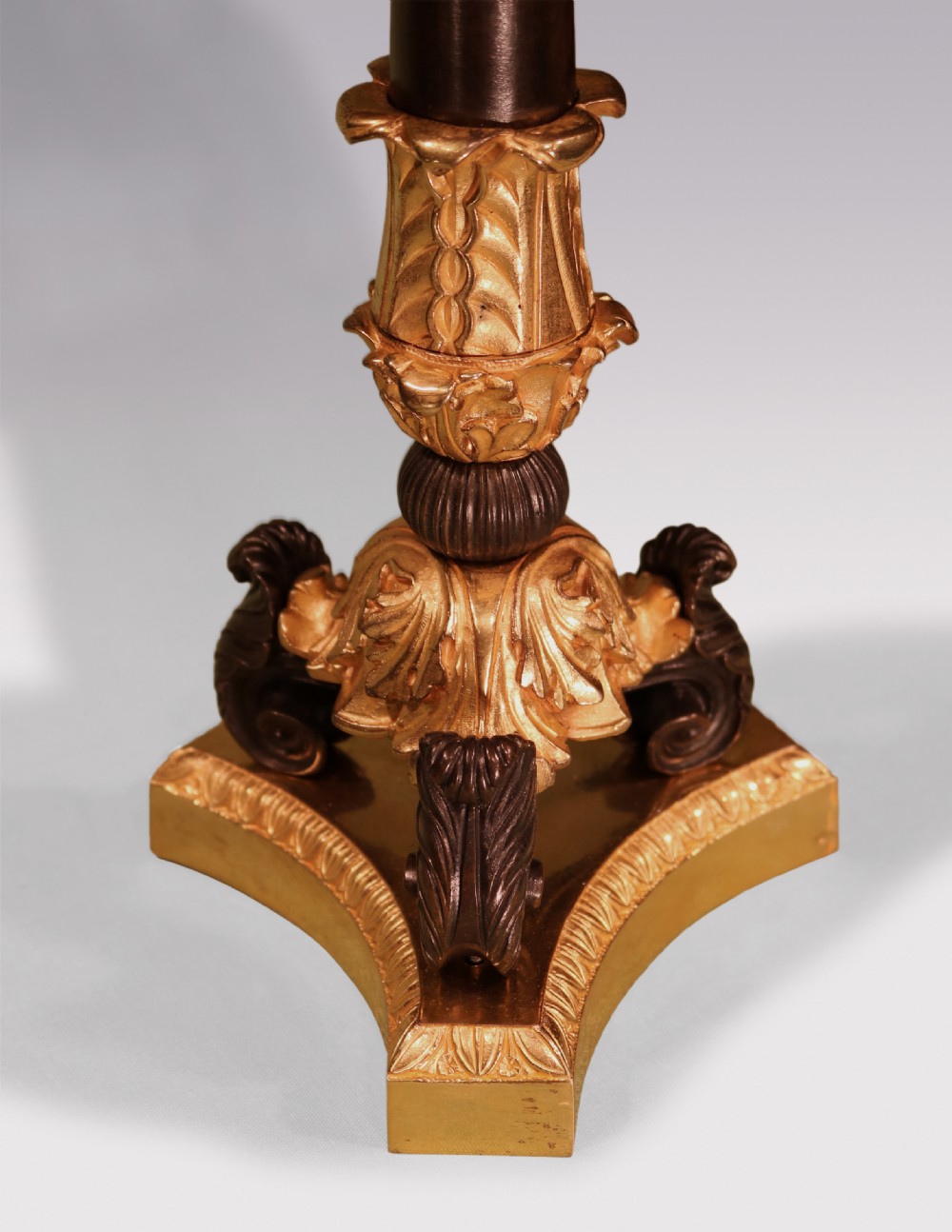 A pair of 19th-century Neoclassical table lamps featuring dark patinated bronze columns, ornate gilt-bronze acanthus leaf mounts, tripod scrolled bases, and flared fabric shades. View V