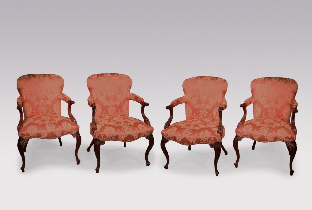 A set of four Hepplewhite period mahogany armchairs upholstered in coral red damask fabric with carved cabriole legs.