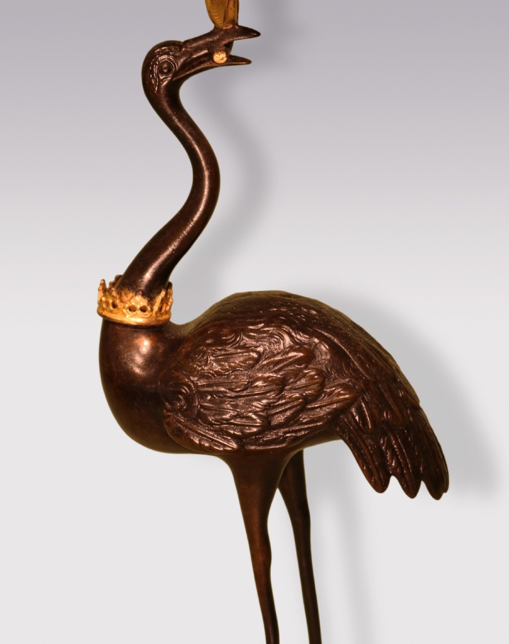 A pair of mid-19th century dark patinated bronze storks standing on rocky gilt ormolu bases, each holding a palm-leaf sconce in its beak. View V