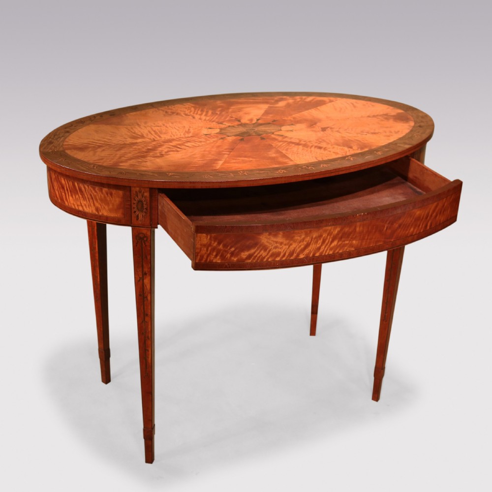 An oval antique satinwood occasional table featuring radial marquetry, crossbanded edges, an inlaid apron, and slender square tapered legs. View III