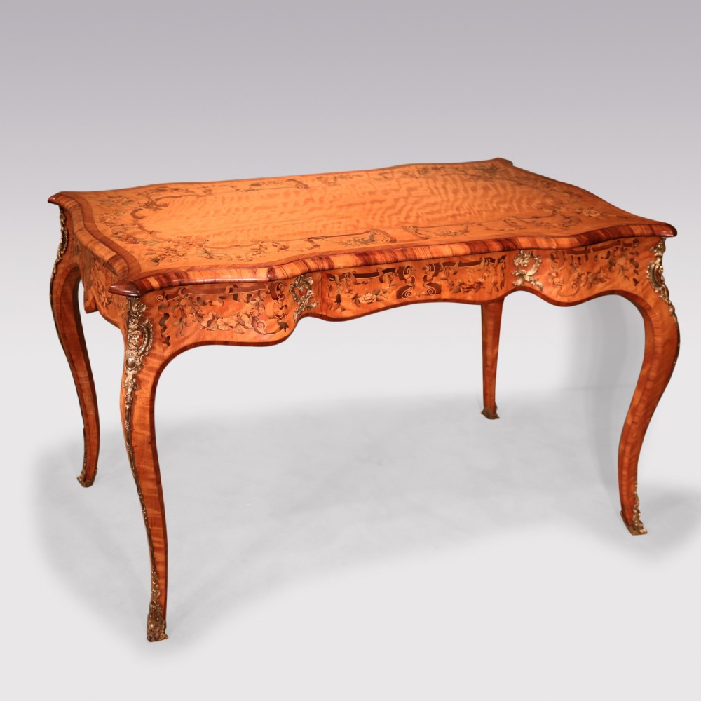 A mid-19th-century serpentine satinwood writing table featuring floral marquetry inlay, calamander banding, gilt-bronze mounts, and cabriole legs.
