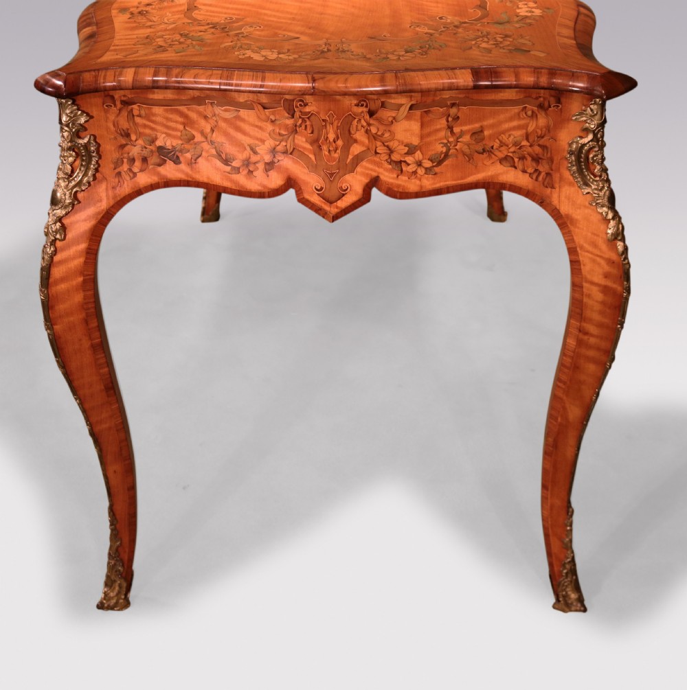 A mid-19th-century serpentine satinwood writing table featuring floral marquetry inlay, calamander banding, gilt-bronze mounts, and cabriole legs. View II