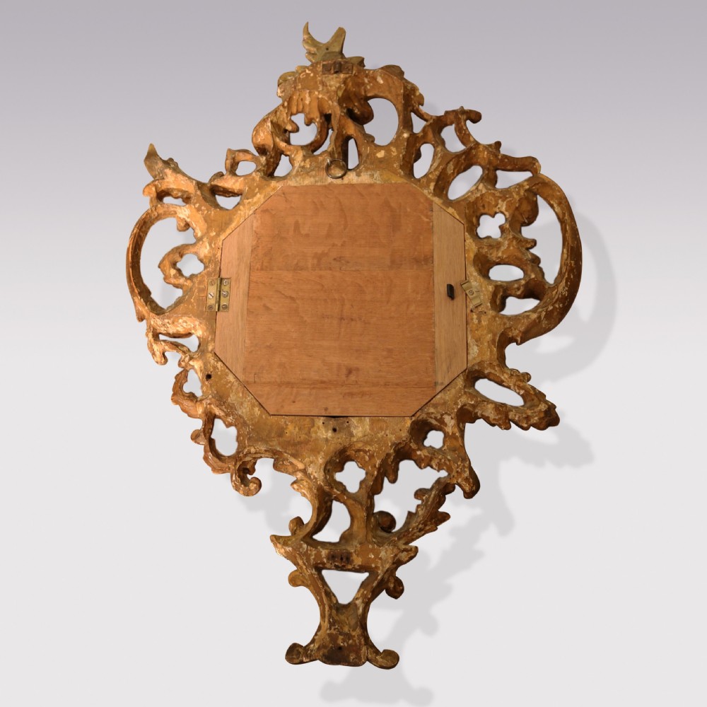 An ornate George III period carved giltwood cartel wall clock featuring asymmetrical rococo scrollwork, acanthus leaf motifs, and a circular dial with Roman numerals. View IV